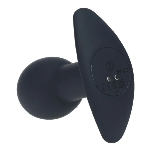 A black silicone device with a rounded base and a flat, winged handle. The handle features a power button, charging port, and certification symbols.