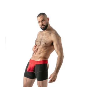 A muscular, bearded man with short hair poses confidently in black and red boxer shorts against a plain white background.