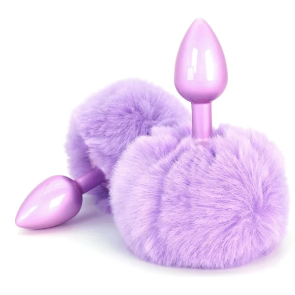 toyjoy-bunnytail-purple-1 Two lavender-coloured plugs with fluffy, faux fur bases, resembling rabbit tails, are shown against a white background.